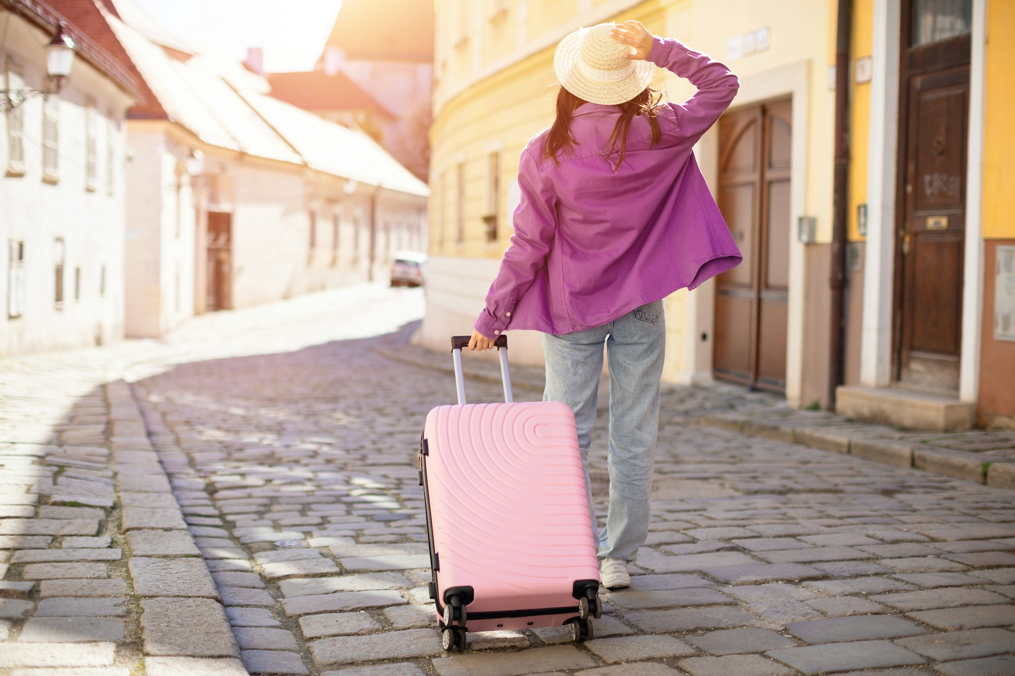 Woman traveler walking with suitcase in old town